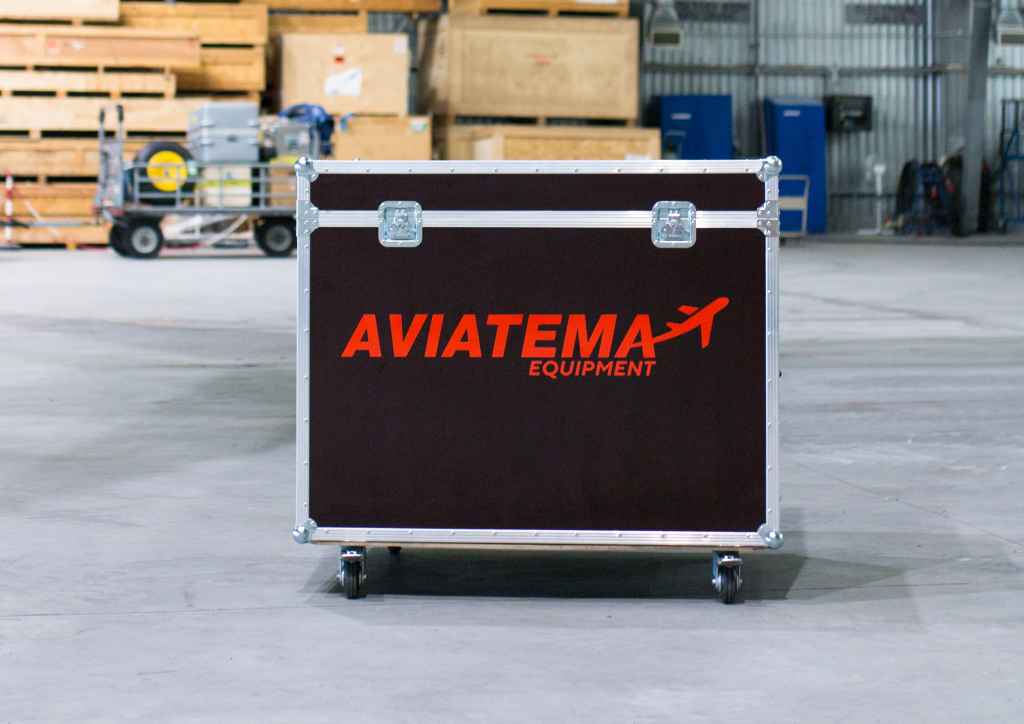A hard transportation case in black and red sitting in a warehouse.